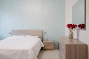 a bedroom with a bed and a vase with red flowers at Lara’s House in San Giovanni Lupatoto