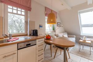 eine Küche und ein Wohnzimmer mit einem Tisch und einem Esszimmer in der Unterkunft Strandhafer im Haus Südstrand in Wyk auf Föhr