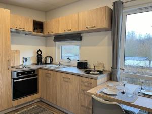 eine Küche mit Holzschränken, einem Tisch und einem Fenster in der Unterkunft Holiday Home Tiny Haus mit schönem Seeblick by Interhome in Wemding