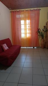 sala de estar con sofá rojo y ventana en La villa du manguier, en Le Vauclin