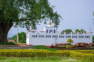 un grand bâtiment blanc avec un dôme d'or au-dessus dans l'établissement Siddhartha Guest House, à Rummindei