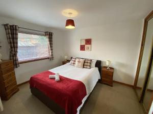 ein Schlafzimmer mit einem Bett mit einer roten Decke in der Unterkunft Holiday Home Penny Lodge by Interhome in Aviemore