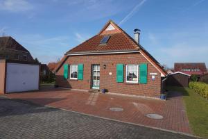 una casa in mattoni con finestre con persiane verdi e un vialetto di Ferienwohnungen Höhn ad Altfunnixsiel