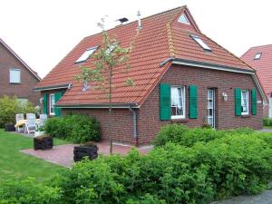 una casa di mattoni con il tetto rosso e le persiane verdi di Ferienwohnungen Höhn ad Altfunnixsiel