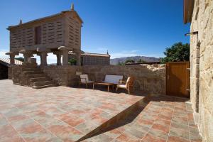 a patio with two chairs and a stone wall at Casa Nova in Carnota