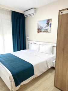 a bedroom with a large bed with blue curtains at Navarino Luxe Suites in Perea