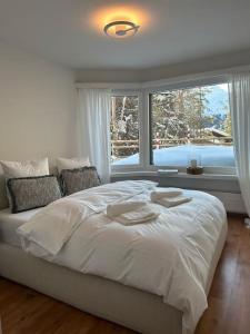 um quarto com uma grande cama branca e uma janela em Wonderful cosy apartment in St. Moritz em St. Moritz