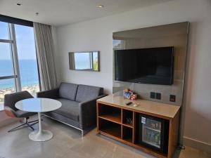 ein Wohnzimmer mit einem Sofa, einem TV und einem Tisch in der Unterkunft Hotel Nacional in Rio de Janeiro