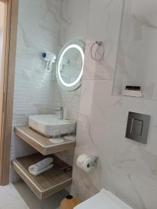 a white bathroom with a sink and a mirror at Navarino Luxe Suites in Perea