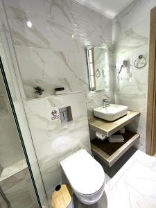 a white bathroom with a toilet and a sink at Navarino Luxe Suites with Sea View in Perea