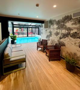 uma sala de estar com um sofá e cadeiras e uma piscina em Le Cornouaille Hotel & Spa em Bénodet