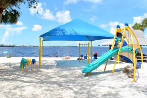 einen Spielplatz mit Rutsche und Sonnenschirm am Strand in der Unterkunft Luxury Condo at Cape Harbour Marina, Water Views! in Cape Coral