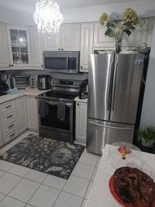 a kitchen with a stainless steel refrigerator and a table at JORDAN'S NEST in Ajax