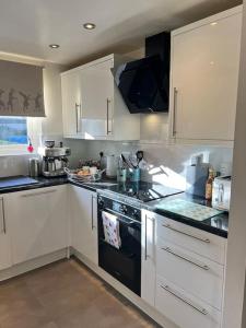 a kitchen with white cabinets and a black stove top oven at Purfleet Apartment-Free Parking in Purfleet