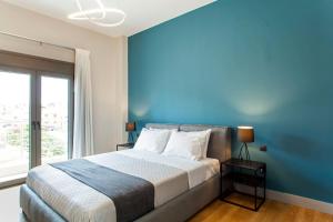 een slaapkamer met een groot bed met een blauwe muur bij Minimal Loft Art with Sea View Over Heraklion Harbour in Heraklion