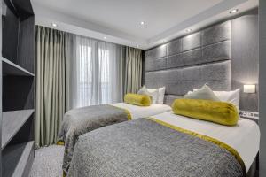 a hotel room with two beds with yellow pillows at Mornington Hotel London Victoria in London