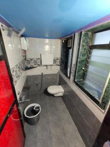 a small bathroom with a toilet and two windows at SHANTI GUEST HOUSE in Srīvardhan