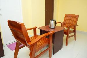 Duas cadeiras de madeira e uma mesa com uma chaleira de chá. em H2 Residency em Ramanathapuram