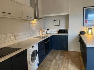 a kitchen with blue cabinets and a washing machine at 48 South St in Alderley Edge
