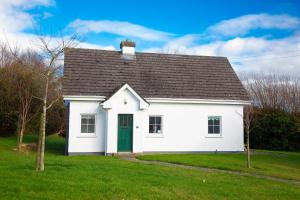 a white house with a green door in a yard at Brittas Bay Holiday Village No 32 in Brittas Bay