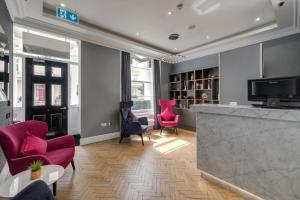a living room with pink chairs and a bar at Mornington Hotel London Victoria in London