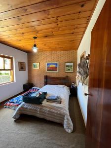 1 dormitorio con cama y techo de madera en Casa aconchegante próximo ao Capivari, en Campos do Jordão