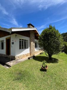 una pequeña casa blanca con un árbol en el patio en Casa aconchegante próximo ao Capivari, en Campos do Jordão