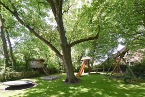 un parque infantil con un árbol y un columpio en Ferienwohnungen Janssen-Graalfs, en Wangerland