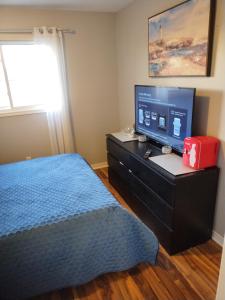 a bedroom with a bed and a desk with a computer monitor at Ajax Holiday in Ajax