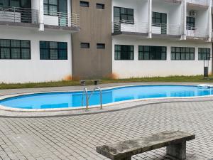 a swimming pool with a bench in front of a building at The Time in Kota Samarahan