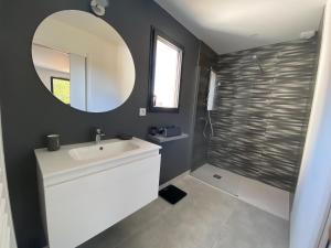 uma casa de banho com um lavatório branco e um espelho. em Villa avec piscine et spa proche circuit 24H Le Mans em Changé