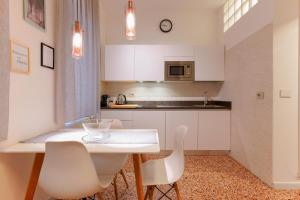a kitchen with a white table and white chairs at M&M Apartment in Bologna