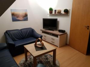uma sala de estar com um sofá e uma televisão em Ferienwohnung Schwalbennest em Carolinensiel