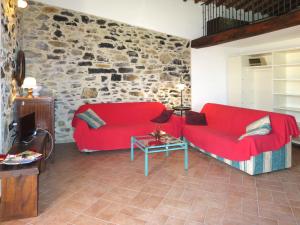 een woonkamer met een rode bank en een stenen muur bij Apartment Fienile by Interhome in Sasso Pisano