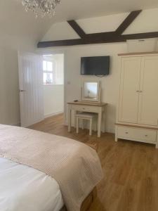 Schlafzimmer mit einem Bett, einem Schreibtisch und einem TV in der Unterkunft Chillout!! Sussex Flint Cottage- HotTub - Goodwood in Eartham