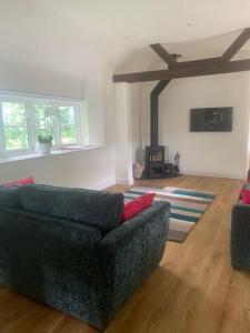 ein Wohnzimmer mit einem schwarzen Sofa und einem Kamin in der Unterkunft Chillout!! Sussex Flint Cottage- HotTub - Goodwood in Eartham