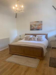 a bedroom with a large wooden bed with a chandelier at Chillout!! Sussex Flint Cottage- HotTub - Goodwood in Eartham