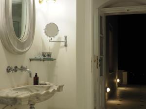 un baño con lavabo y espejo en The Palm Rock, Finikia Santorini, en Foinikiá 69 fotos más