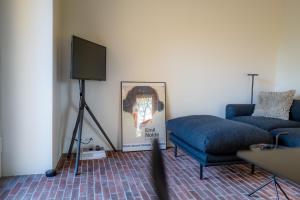a living room with a blue couch and a television at AMTENBRINKSHOF Appartements in Gütersloh