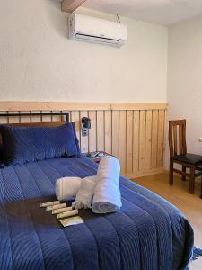 Un dormitorio con una cama azul con toallas. en La Petite France, en San José de Maipo