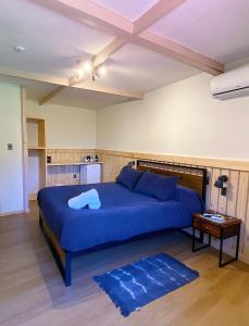 a bedroom with a large blue bed and a table at La Petite France in San José de Maipo