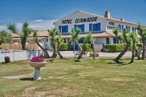 un bâtiment avec un planteur dans une cour plantée de palmiers dans l'établissement Clamador, à Saintes-Maries-de-la-Mer