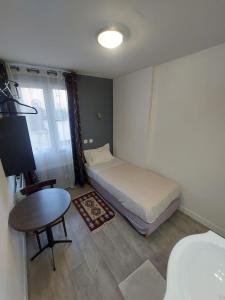 a small bedroom with a bed and a table at Le Kleber in Montreuil