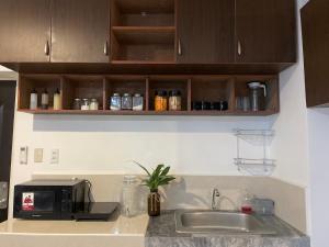 a kitchen counter with a sink and a microwave at Affordable Tourist Studio Condo near Mactan Airport by A&C in Pusok