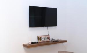 a flat screen tv on a wall with a shelf at Politeama house in Palermo