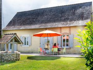 dos personas sentadas en una mesa bajo un paraguas delante de una casa en Gîte Saint-Christophe-en-Champagne, 5 pièces, 8 personnes - FR-1-410-192, en Saint-Christophe-en-Champagne