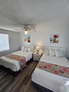 a bedroom with two beds and a ceiling fan at Island Motel OBX in Manteo