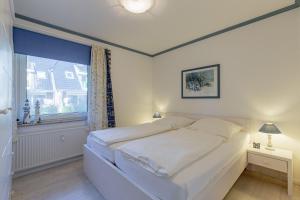 uma cama branca num quarto com uma janela em Wohnen am Südstrand 11 em Wyk auf Föhr