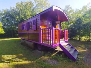 un vagone viola parcheggiato in un campo di Séjour Bucolique en Roulotte au Cœur d'une Ferme Familiale en Sarthe - FR-1-410-229 a Chantenay-Villedieu