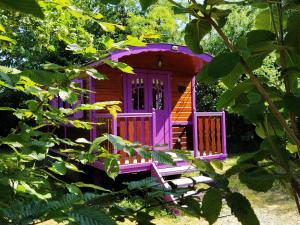 una casetta da gioco viola e rossa in un giardino di Séjour Bucolique en Roulotte au Cœur d'une Ferme Familiale en Sarthe - FR-1-410-229 a Chantenay-Villedieu